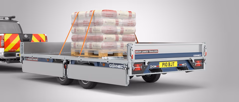 Brian James Connect: rimorchio a pianale con sponde in carico, pallet di materiali edili assicurati con cinghie.