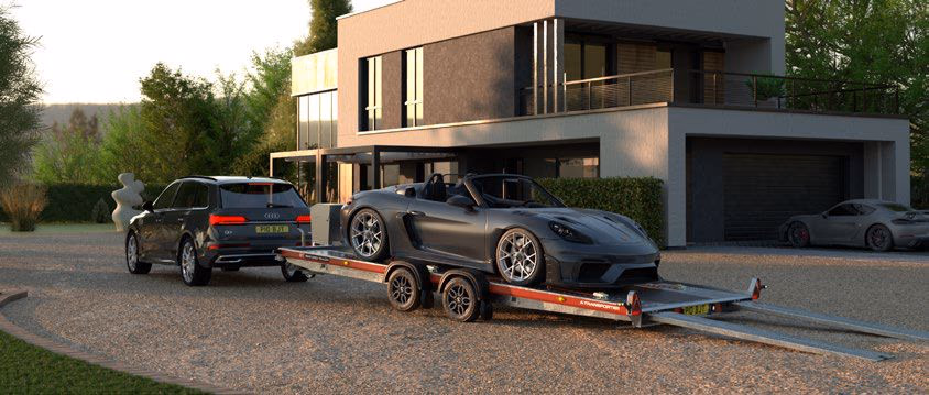 Porsche grigia su un rimorchio aperto a pianale ribassato Brian James A Transporter, trainato da un SUV.