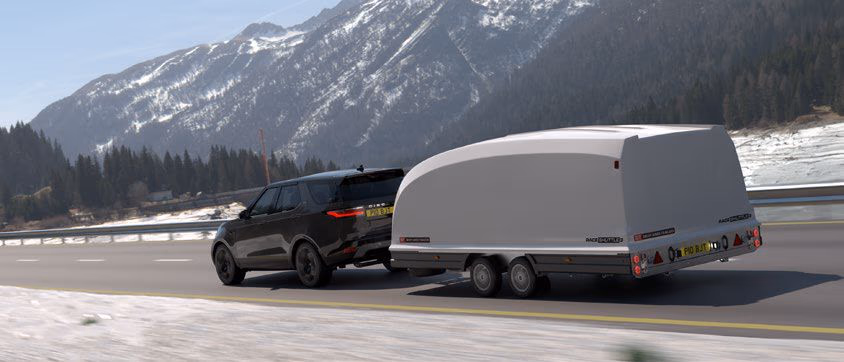 Rimorchio chiuso aerodinamico Brian James Race Shuttle trainato su strada di montagna innevata.