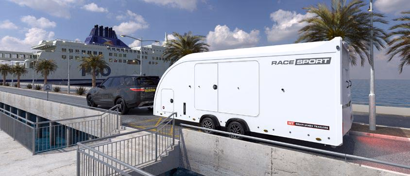 Rimorchio chiuso per trasporto auto Brian James Race Sport bianco, trainato da un SUV su una banchina portuale.